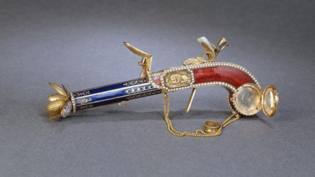 Ce pistolet à parfum ressemble en effet à un vrai pistolet, si ce n'est ses couleurs, bleu roi et pourpre, ainsi que ses dorures dont une fleur s'ouvrant au bout du canon