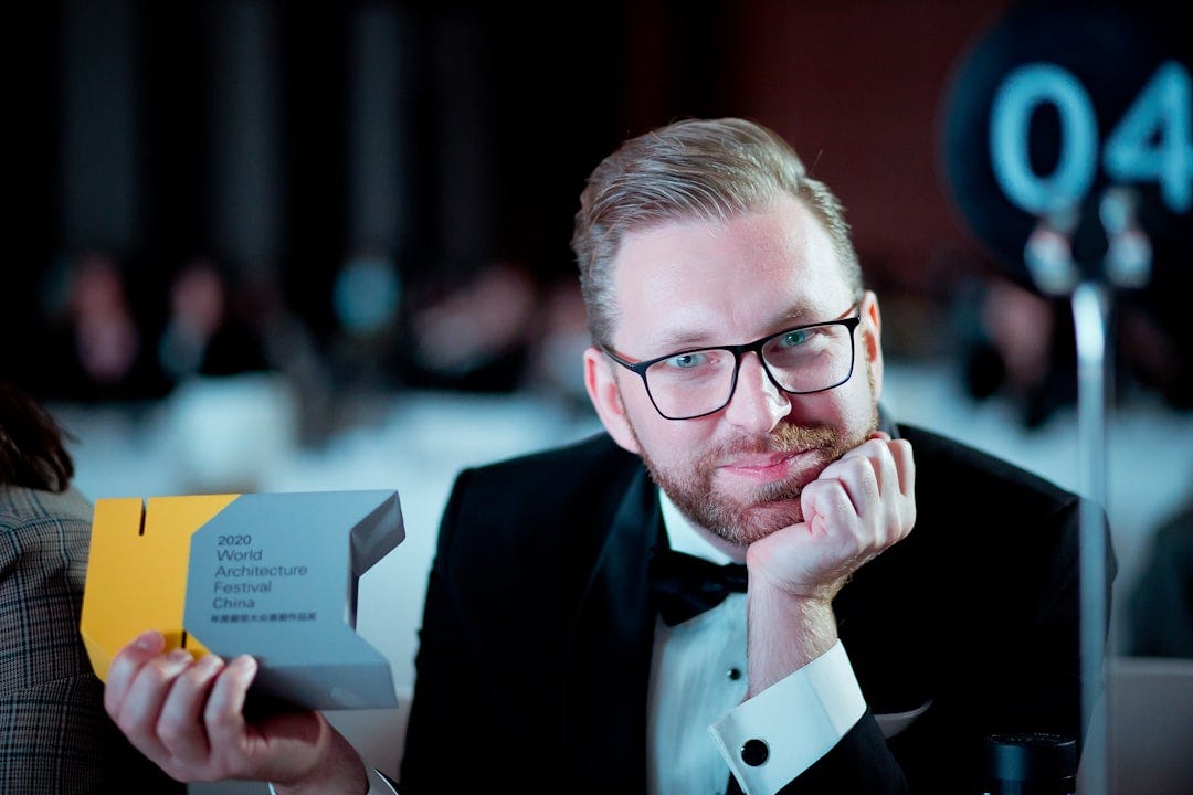 man in black suit jacket wearing eyeglasses