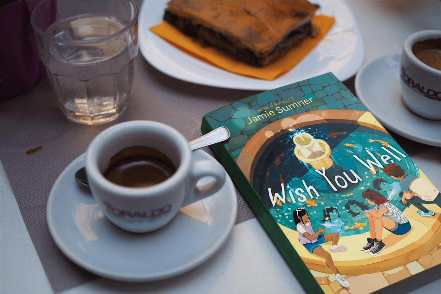 book Wish You Well by Jamie Sumner on a table next to coffee and a brownie book Wish You Well by Jamie Sumner on a table next to coffee and a brownie