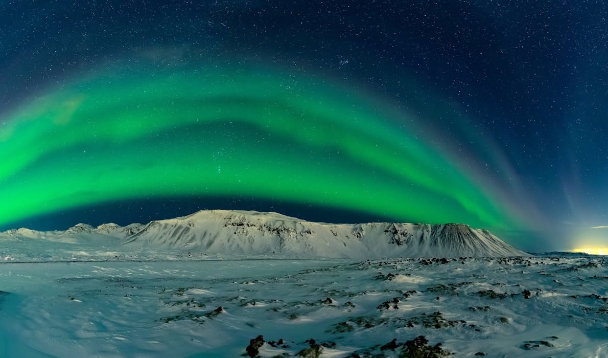 The Northern Lights make an appearance over snowy mountains