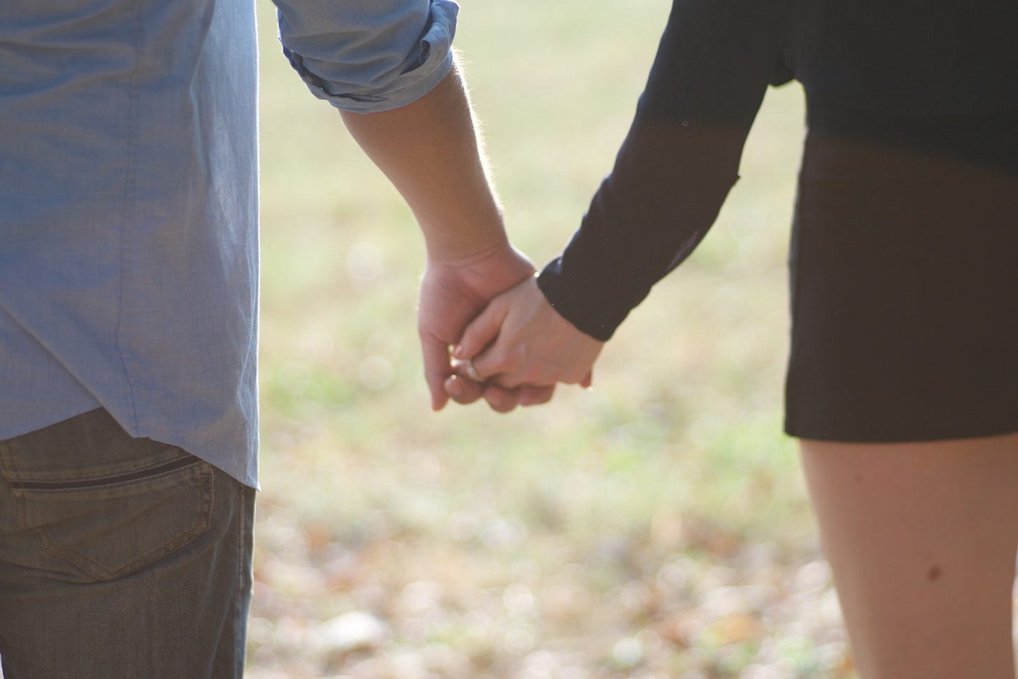 A couple hold hands in the sunlight.