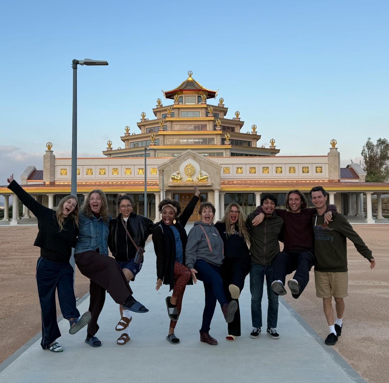 Nine volunteers jumping and celebrating in front of the illuminated Buddhist temple at golden hour in southern Spain. Nine volunteers jumping and celebrating in front of the illuminated Buddhist temple at golden hour in southern Spain.