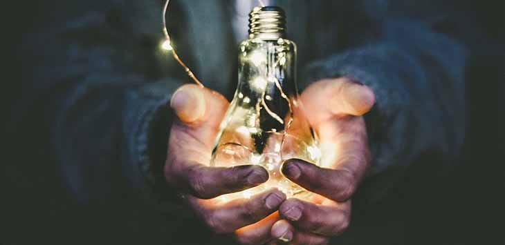 Photo of man holding an illuminated lightbulb.