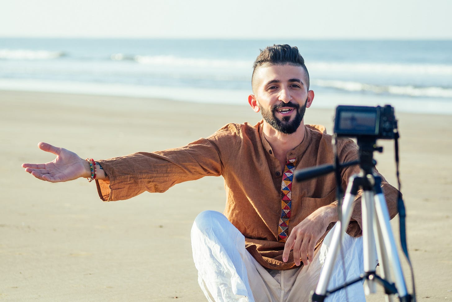 man on the beach filming on a cellphone mounted on a tripod