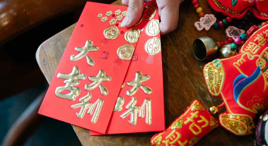 A wooden table with red paper with gold decor and decorations around it