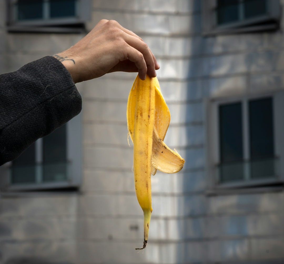 A hand holds up a banana peel.
