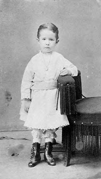 portrait of a child standing next to a chair