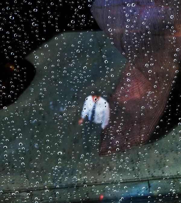 An illustration of a man wearing shirtsleeves and a tie behind a pattern of what looks like raindrops on glass. 