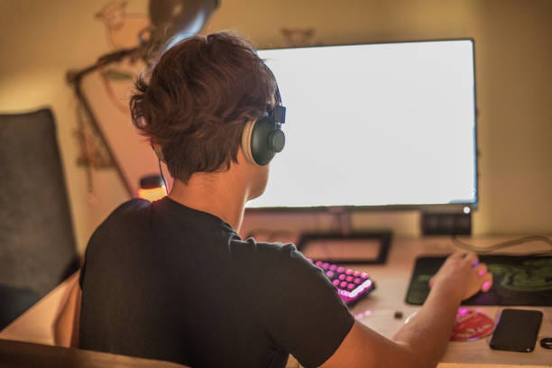 teenager boy playing multiplayer video game on computer wearing headphones - teenager staring at screen stock pictures, royalty-free photos & images