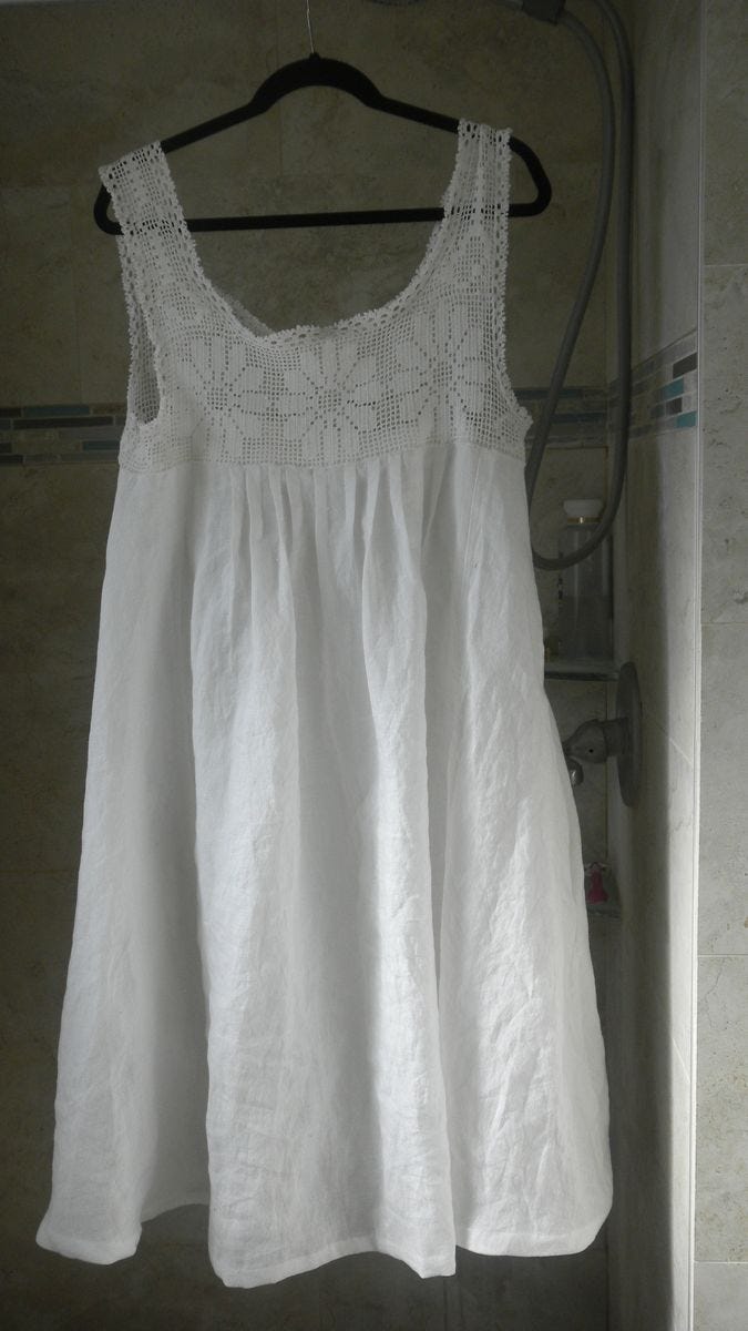 This may contain: a white dress hanging on a clothes rack