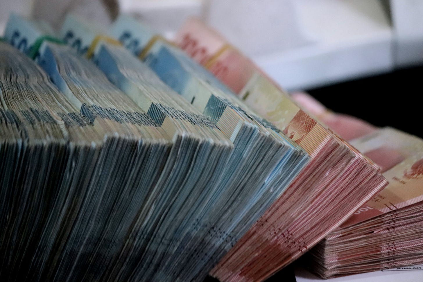 A close-up of Indonesian banknotes, representing the domestic purchasing power currently under pressure from global and fiscal headwinds.
