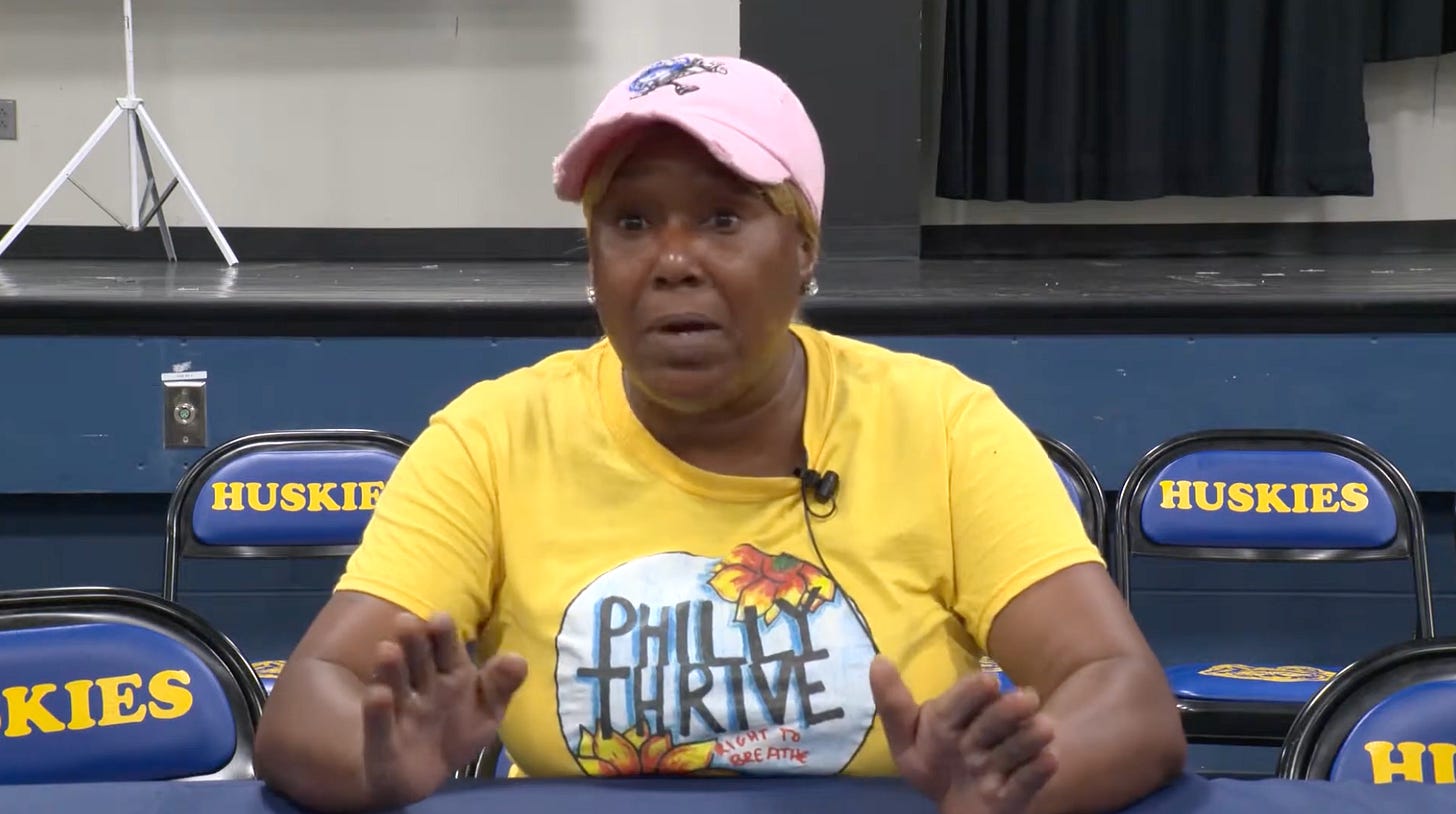 A woman speaks at a public meeting about a refinery fire