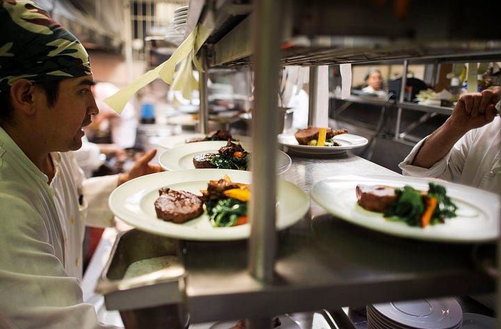 people in a restaurant in New York, a restaurant kitchen with plates, a busy dining room in a NYC restaurant