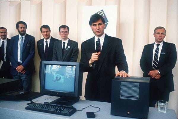 A group of men in suits standing in front of a computer

Description automatically generated