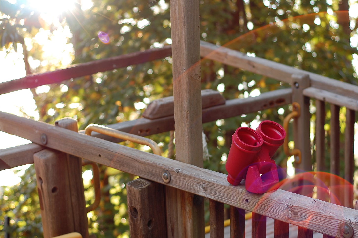 Closeup of a swingset with red binoculars mounted on top, with solar flares