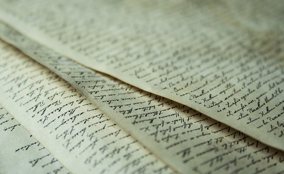 Foto de papéis de aparência envelhecida, preenchidos com texto manuscrito em caligrafia caprichada e linhas retas, embora os papéis não sejam pautados. As folhas estão meio sobrepostas umas às outras, cada uma deixando escapar um pedaço da debaixo pelo seu lado esquerdo.