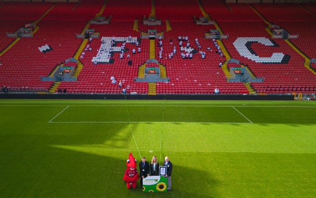 It’s difficult to make out the thin lanyard that runs a long length of a football field, with a mascot and officials standing at the end, with a large card with sunflowers on it.