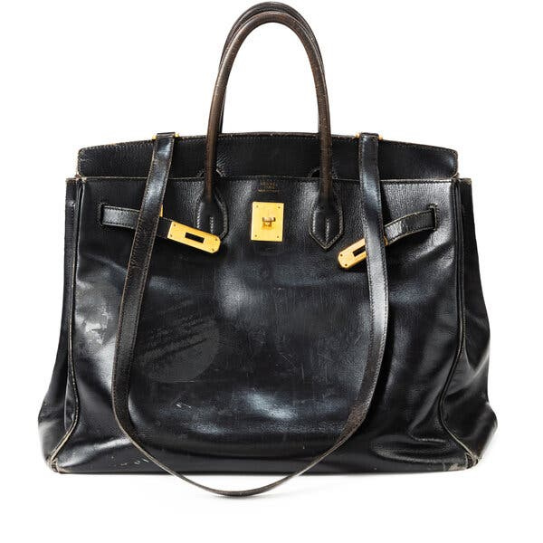 A black bag is seen with a leather strap hanging down in front of it.