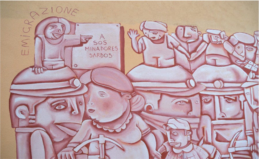 Murale sui toni del rosa: un gruppo di uomini e donne, con corpi squadrati e grandi teste come se fossero scolpite sulla pietra, stanno tutte vicine. Tre uomini in primo piano indossano elmetti da minatore e stringono un piccone. Un donna in primo piano tiene per mano un bambino. Dall’elmetto del primo minatore spunta una persona più piccola che indica un cartello con la scritta “A sos minadores sardos”. Dietro, la scritta “emigrazione”.