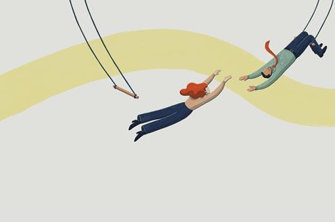 Woman letting go of trapeze to be caught by man