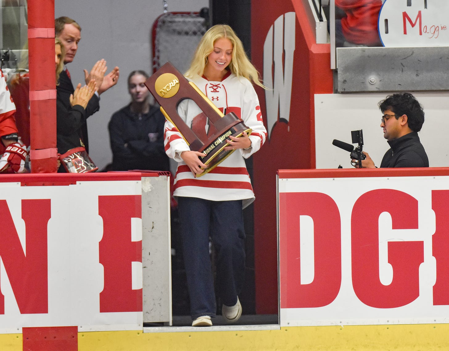 Vivian Jungels carries the NCAA national championship trophy out of the Badgers tunnel and onto the ice