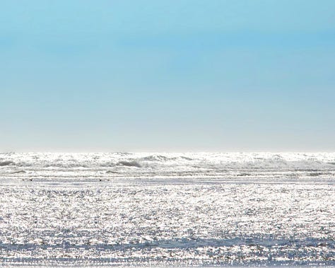 A selection of three images shows: a horizon of blue sky and sparkling ocean; a close-up of glistening sandy beach; a green heart-shaped sea glass.