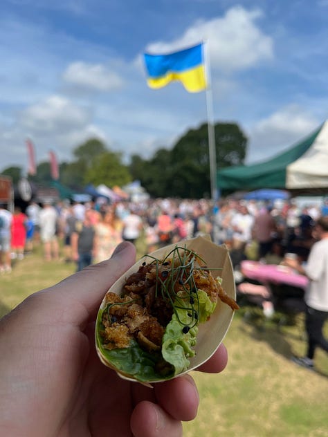 First image is of a hand holding a sample of drink, the second is of a man wearing a yellow and white striped apron at a food festival and the third shows a hand holding a sample of food with a Ukrainian flag in the background.