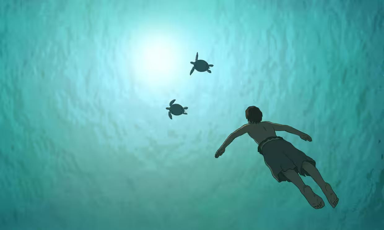 A young man swimming in the ocean with two sea turtles