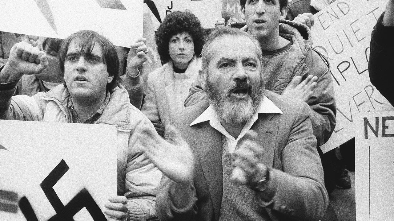 Meir Kahane leading an American Zionist JDL rally, with a Nαzi sign visible beside him — the public theater of militant hatred on American soil. Meir Kahane leading an American Zionist JDL rally, with a Nαzi sign visible beside him — the public theater of militant hatred on American soil.