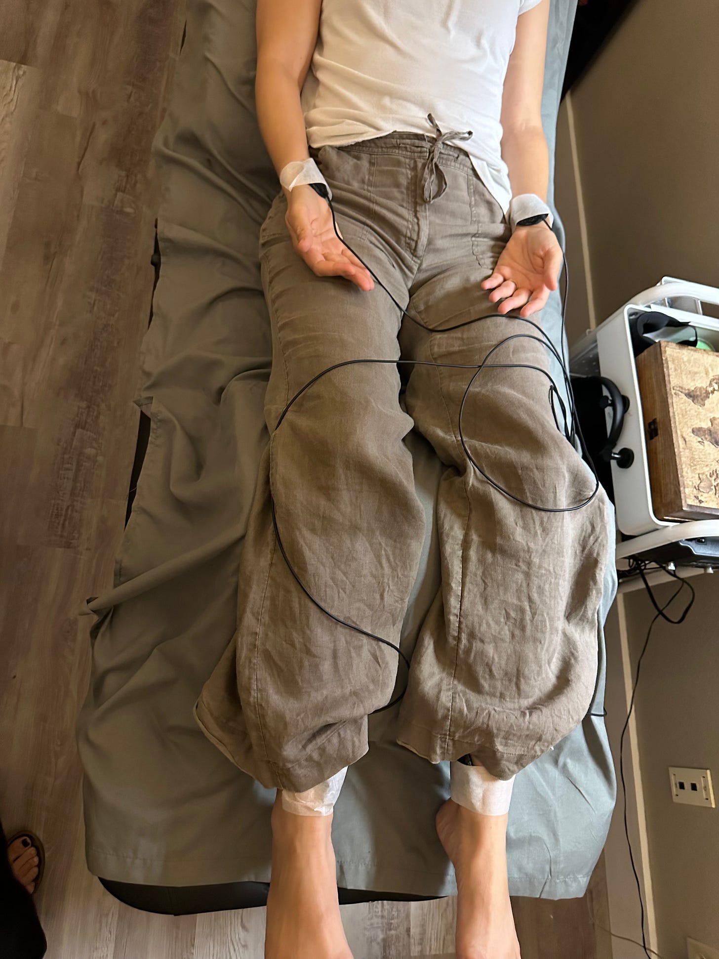Woman's torso on a therapy table with sound sensors paper-taped on her wrists and ankles. Woman's torso on a therapy table with sound sensors paper-taped on her wrists and ankles.