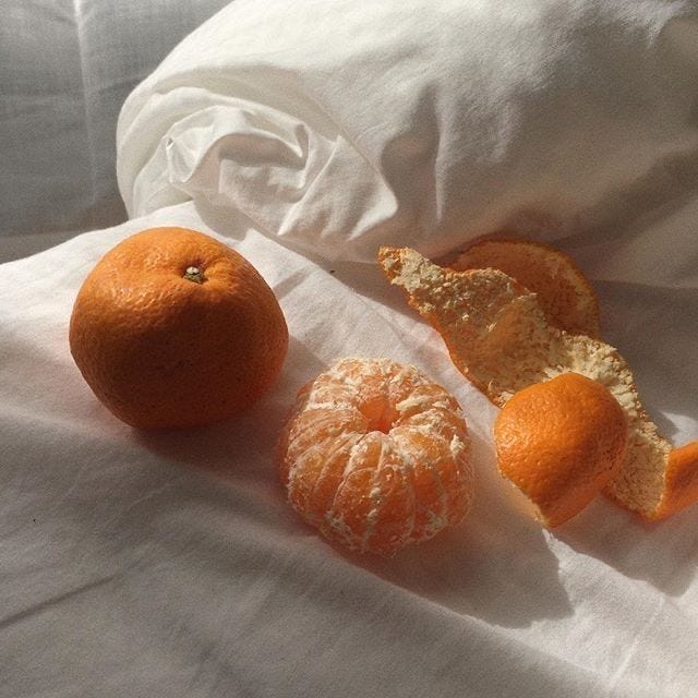 This may contain: three oranges are sitting on a white sheet and one is half peeled, the other half eaten
