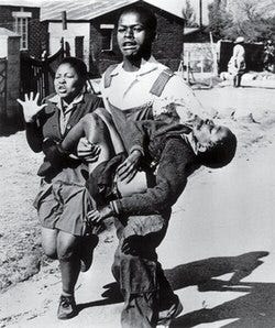 A black and white photo by Sam Nzima ofMakhubu carrying Pieterson's body while Pieterson's sister runs alongside.