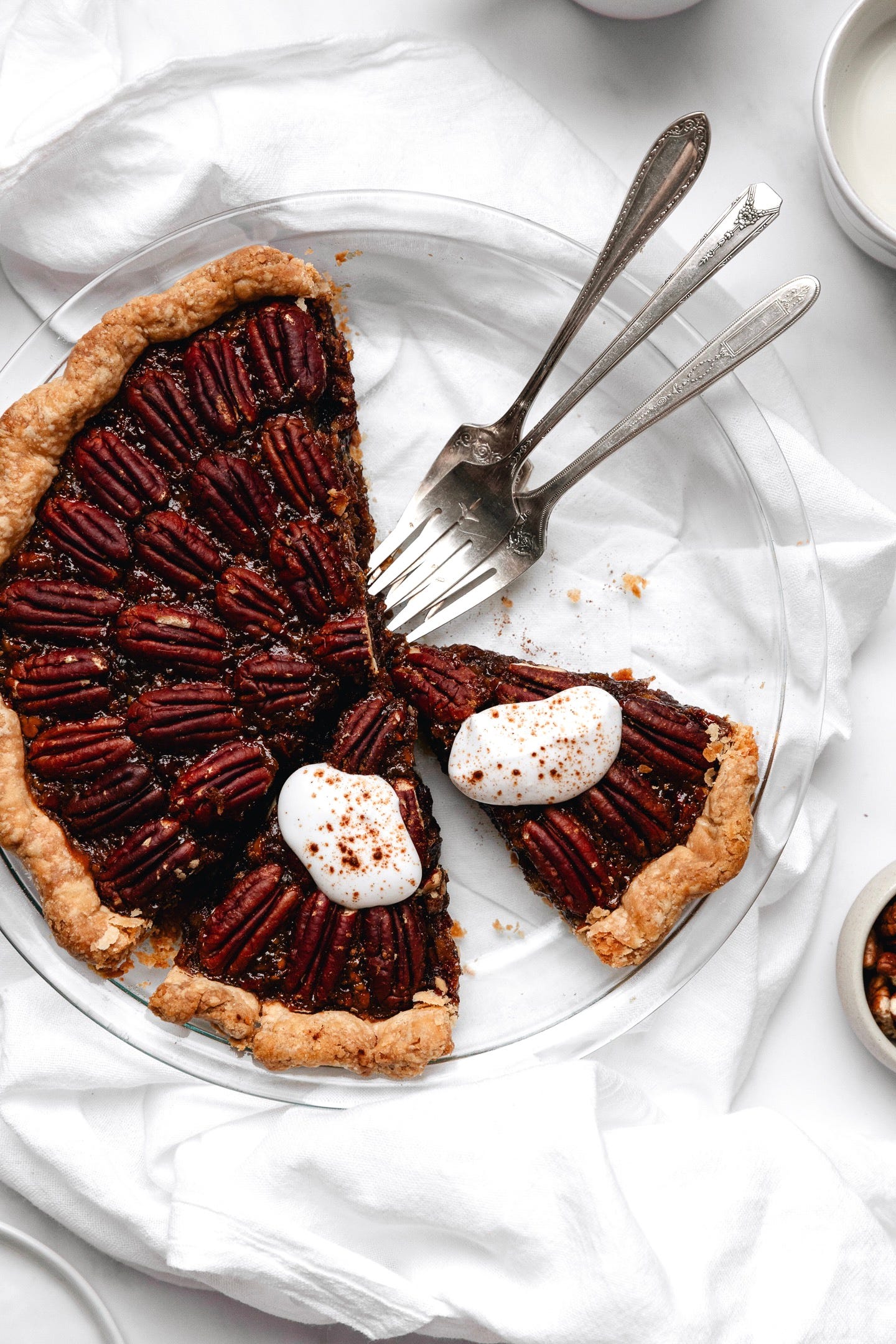 Slices of vegan chai spiced pecan pie in glass pie plate on white background