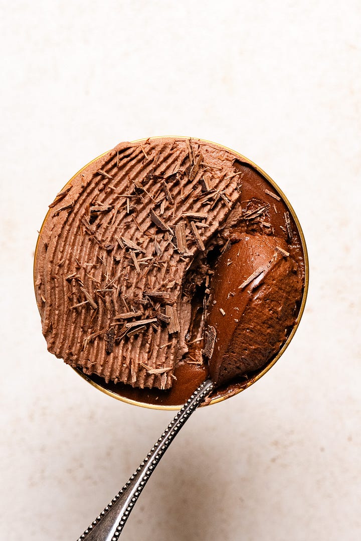 Hazelnut chocolate mousse topped with chocolate whipped cream in glass goblets.