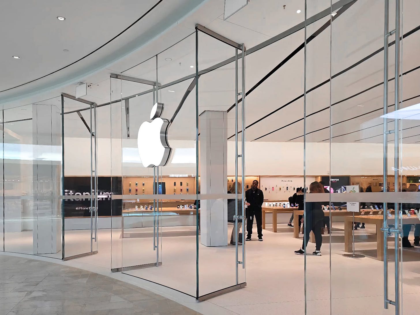 The entrance to Apple Square One. Curved glass panels are split by two sets of swing doors. The entrance to Apple Square One. Curved glass panels are split by two sets of swing doors.