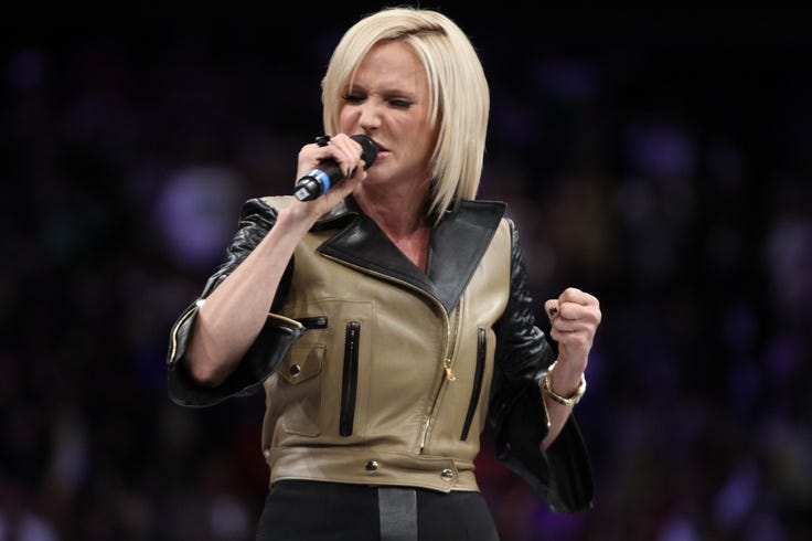 This may contain: a woman with blonde hair and black leather jacket on holding a microphone in her hand This may contain: a woman with blonde hair and black leather jacket on holding a microphone in her hand