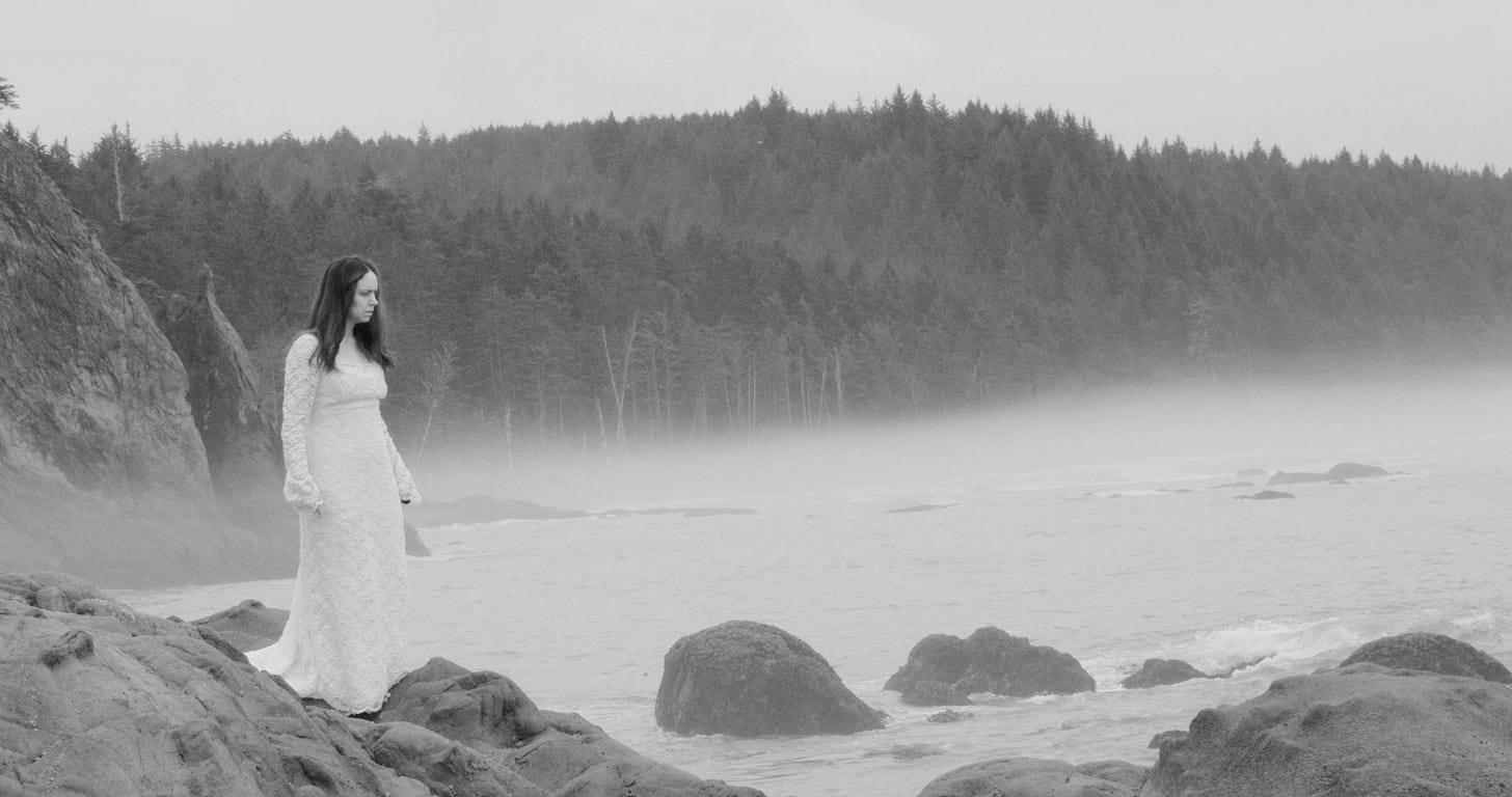 Still from the film The Not with Courtney Hoskins standing in a wedding dress on the shore of the Pacific Northwest in the fog
