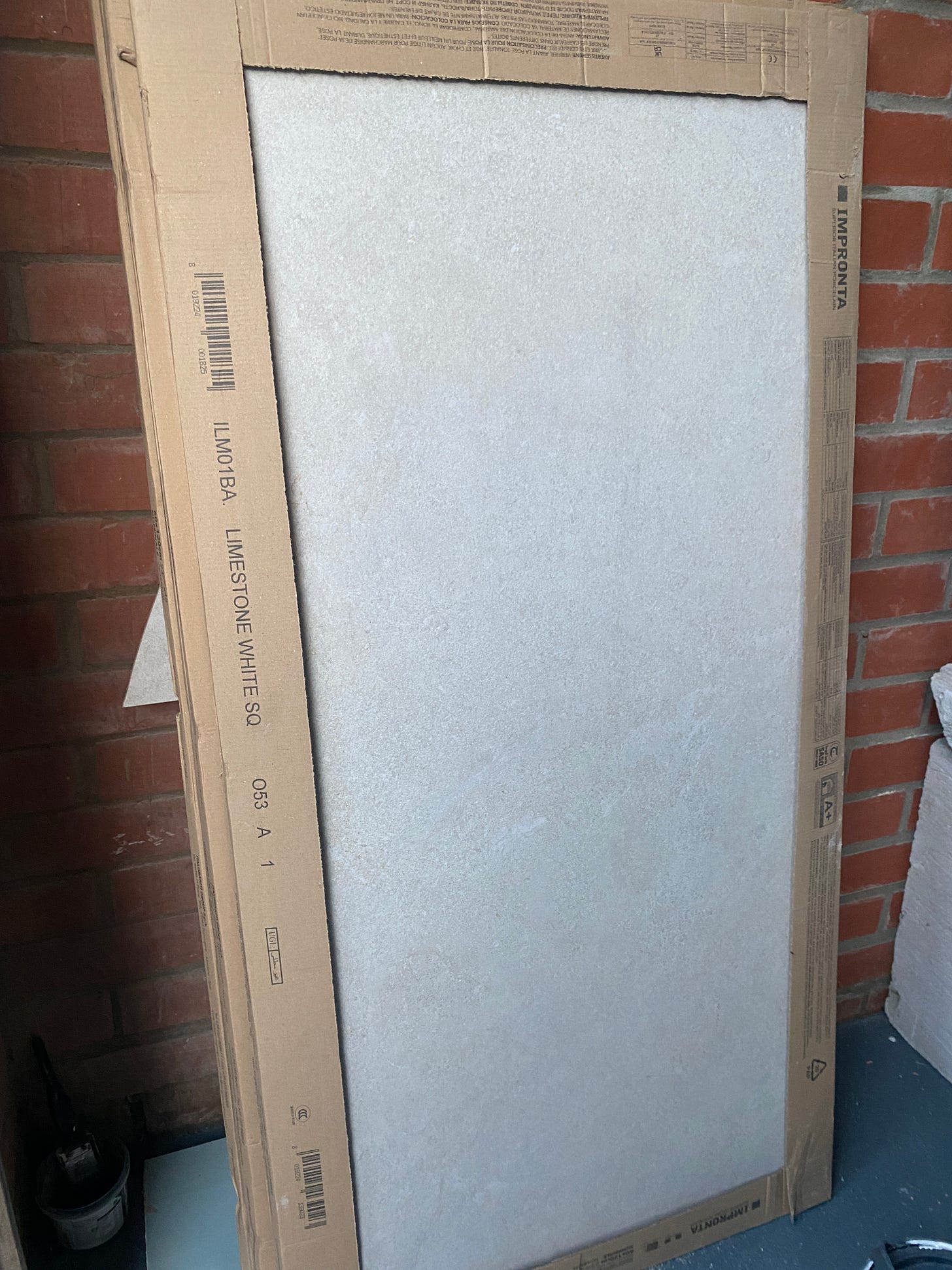 boxes of off-white tiles propped up against the garage wall