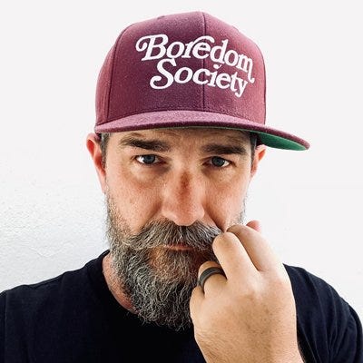 James Kingsley wearing a baseball hat that says "Boredom Society" - one of his design creations. James Kingsley wearing a baseball hat that says "Boredom Society" - one of his design creations.