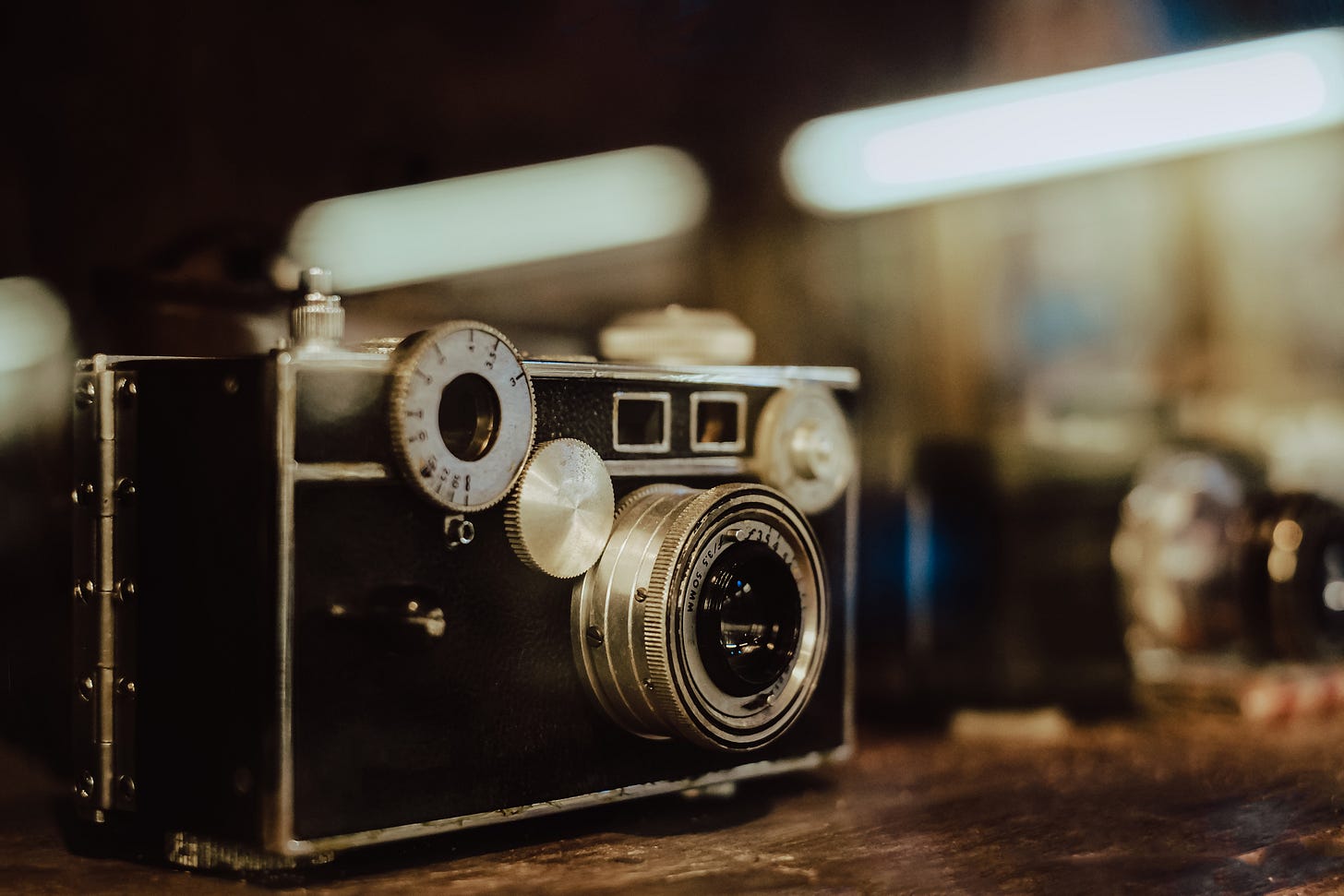 Close-up of an old, vintage camera, on a wooden table, with blurred background.
