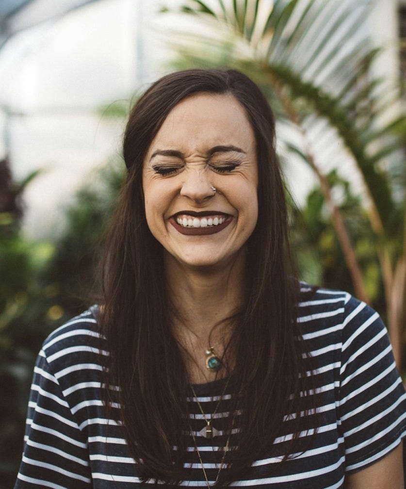 woman smiling while standing in garden woman smiling while standing in garden