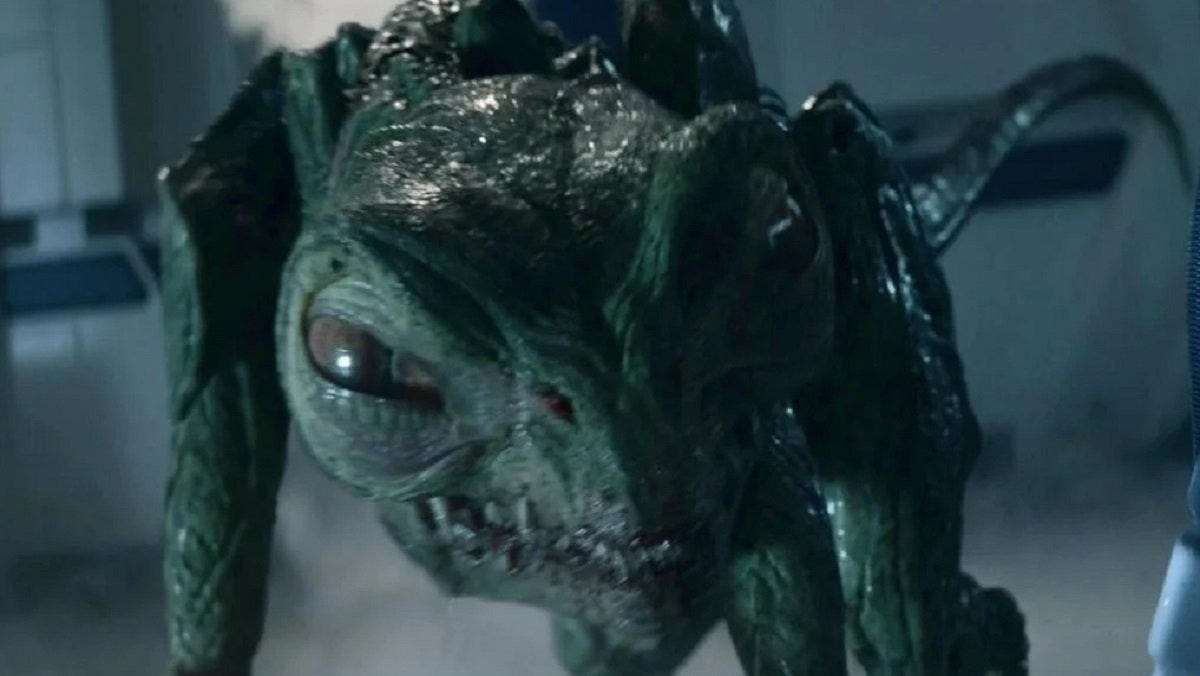 A juvenile Gorn crouches on four legs, showing its large eyes, sharp teeth, and armored green skin. A juvenile Gorn crouches on four legs, showing its large eyes, sharp teeth, and armored green skin.