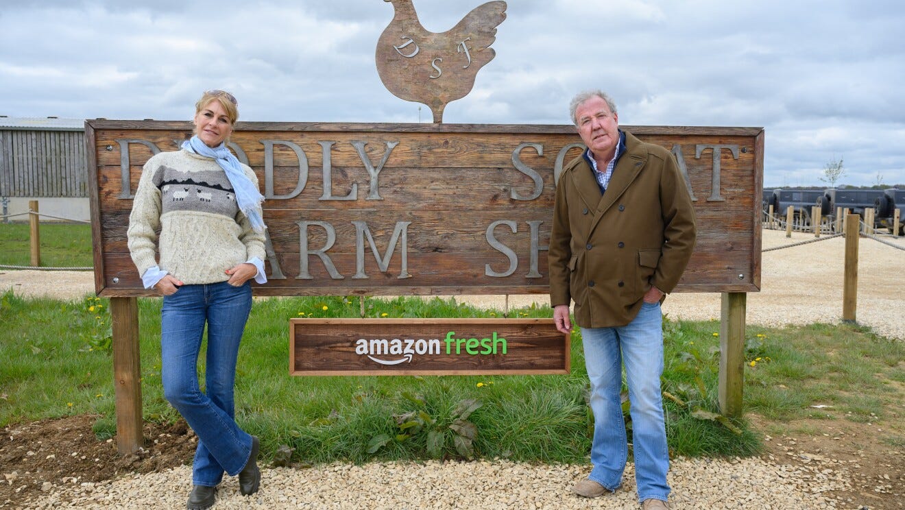 A man and a woman standing in front of a sign on a farm