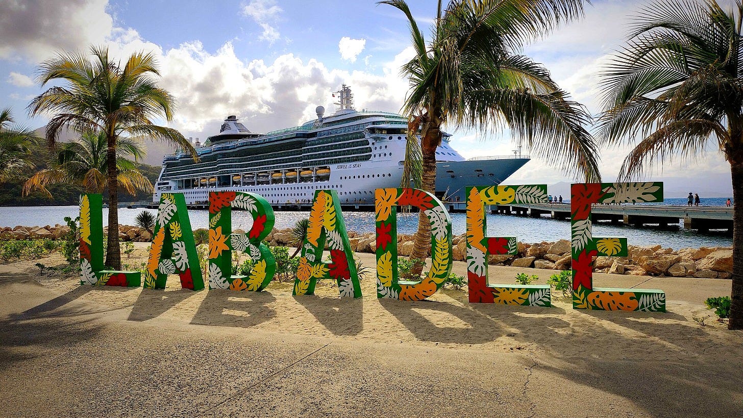 The colorful Labadee sign with a Royal Caribbean ship docked behind it in Haiti. Image: Pvalerian via Wikimedia Commons