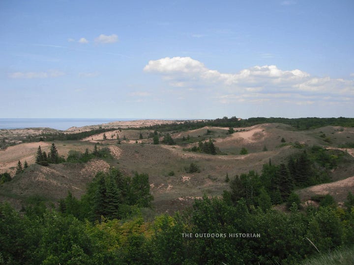 Alt-Text 1: An older photo of the Grand Sable Dunes covered in beach grass. Alt-Text 2: A dusk photo looking down the steep edge of a sand dune toward the water.