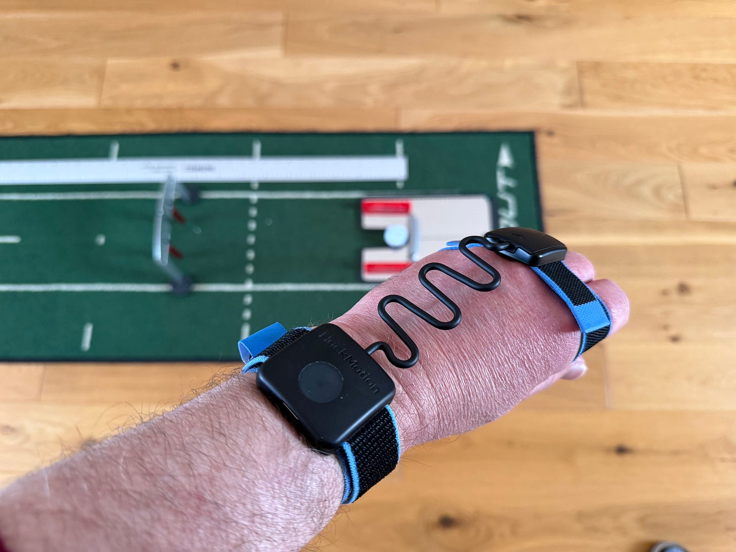 HackMotion wrist sensor in use during an indoor putting session on a home practice mat with training gates
