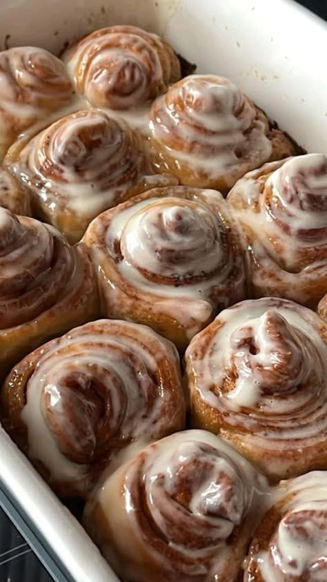 This may contain: a pan filled with cinnamon rolls covered in icing