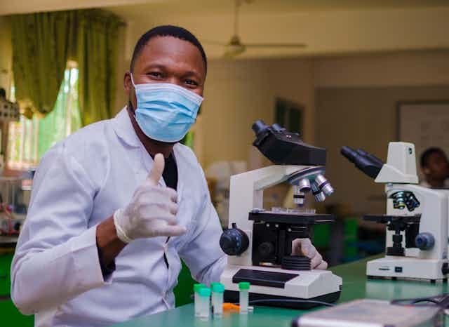 Young man in a laboratory gives a thumbs up.