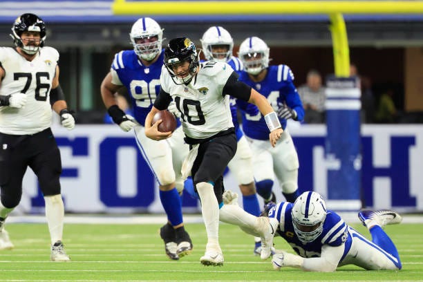 Mac Jones of the Jacksonville Jaguars runs with the ball while being chased by DeForest Buckner of the Indianapolis Colts in the fourth quarter at...