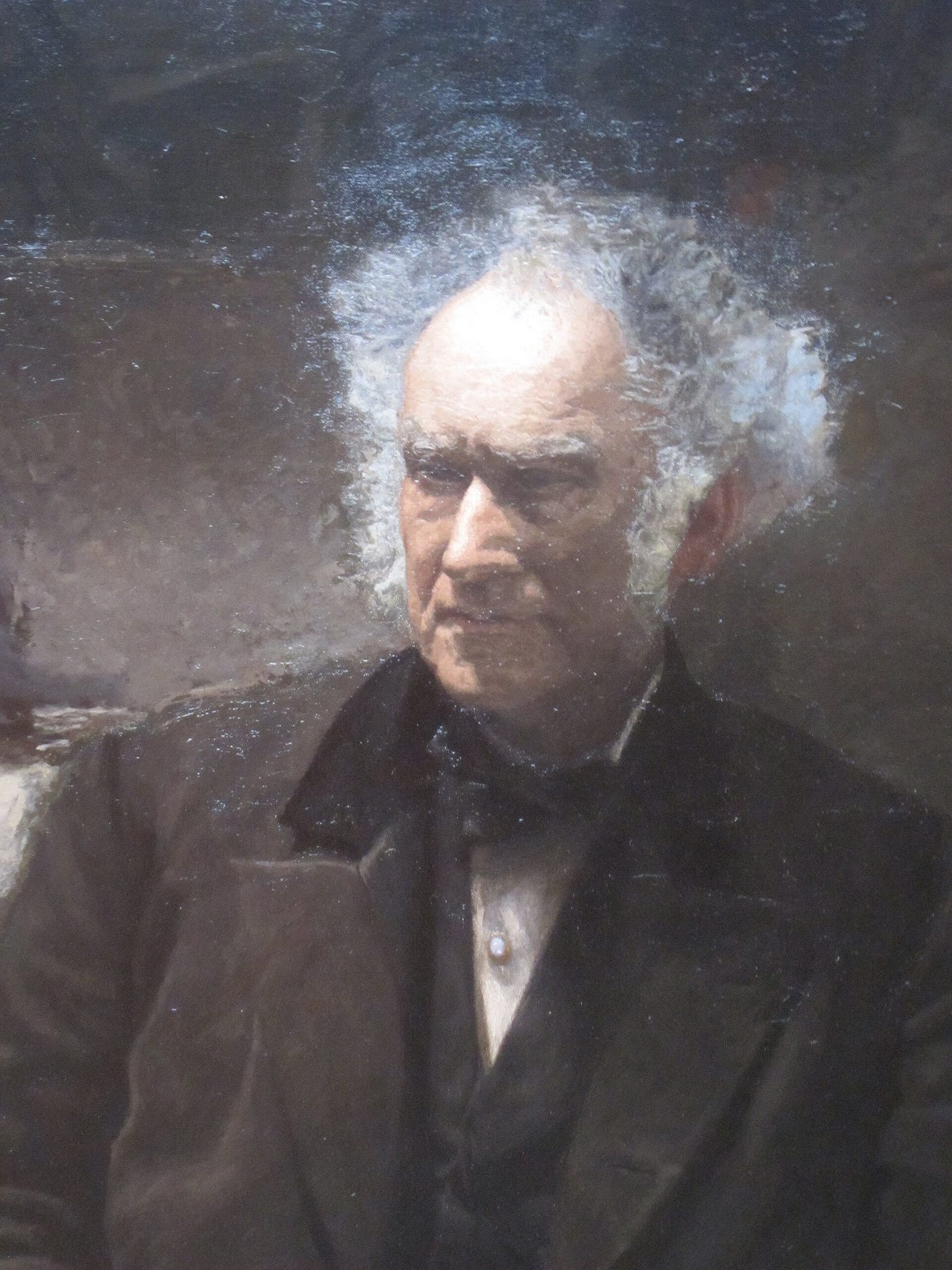 Close view of the surgeon's face, his white hair lit from above, a pale stud on his shirt front. Close view of the surgeon's face, his white hair lit from above, a pale stud on his shirt front.